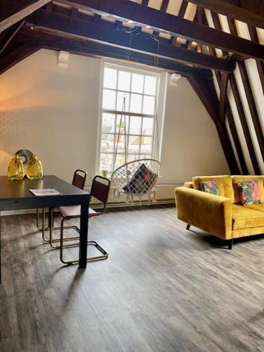 a living room with a yellow couch and a table at Torenkamer Middelburgh in Middelburg