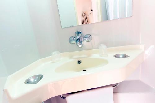 Premiere Classe La Rochelle Nord - Puilboreau في بويلبورو: حمام أبيض مع حوض ومرآة