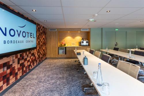 a conference room with a large screen in aoren office at Novotel Bordeaux Centre Ville in Bordeaux
