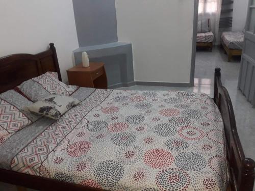 a bedroom with a bed with a comforter on it at Joli Chalet plain-pied avec jardin privatif in Tlemcen