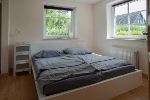 ein Bett in einem Schlafzimmer mit zwei Fenstern in der Unterkunft Ferienwohnung Zimmert in Zimmert