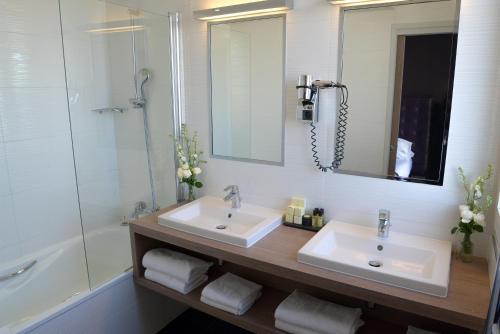 a bathroom with two sinks and a shower and a mirror at Hôtel Saint-Charles in Paris