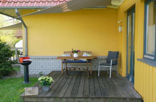 a patio with a table and a chair on a yellow house at De lütte im gulen Hus in Kappeln
