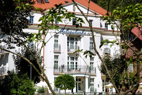 a white building with a sign on it at Małopolanka & Spa in Krynica Zdrój