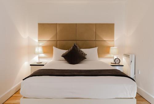 a bedroom with a large white bed with two lamps at StayInn Canary Wharf in London