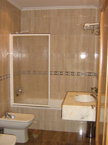 a bathroom with a sink and a toilet and a shower at Hotel Rural Casa Migio in Urbiés