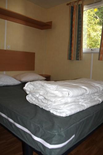 an unmade bed in a bedroom with a window at Camping du lac in Saint-Julien-du-Verdon