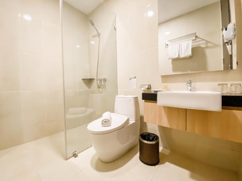 een badkamer met een toilet, een wastafel en een douche bij Grand Paragon Hotel in Jakarta