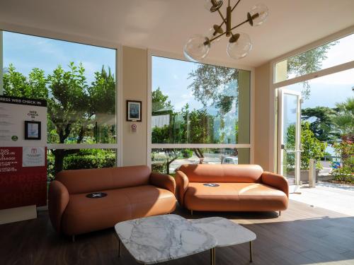 a living room with two brown leather seats and windows at Hotel Leonardo Da Vinci in Limone sul Garda