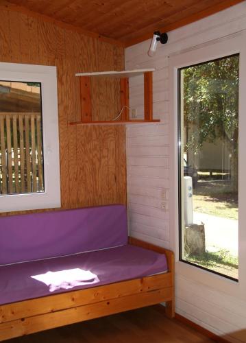 a purple bench in a room with a window at Camping du lac in Saint-Julien-du-Verdon