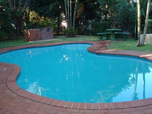 a large blue swimming pool with a picnic table at Newly Renovated 2 bed Apartment - Kingston Estate in Ballito