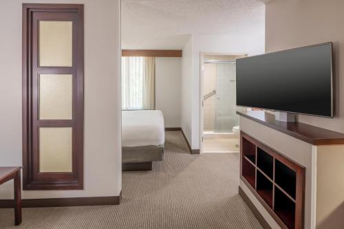 a hotel room with a television and a bedroom at Hyatt Place College Station in College Station