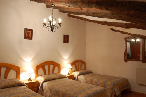 a room with three beds and a chandelier in a building at Alojamientos Casa Ruiz in Archivel