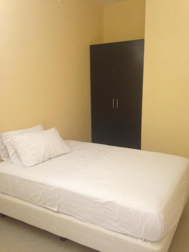 a bed with white sheets and a black door at Casa y Mar Hotel in Tonsupa