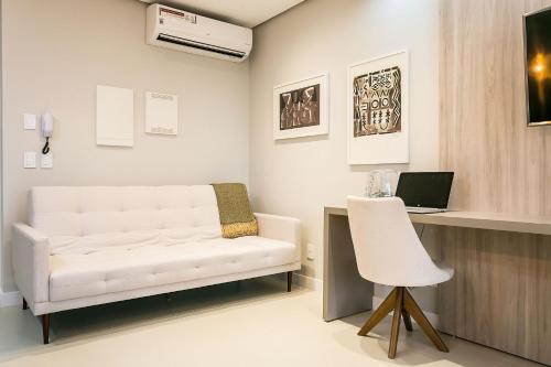a room with a white couch and a desk with a laptop at Gym | Food Hall | 450m from the mall #CA04 in Florianópolis