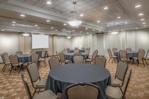 a conference room with tables and chairs and a screen at Hyatt Place College Station in College Station
