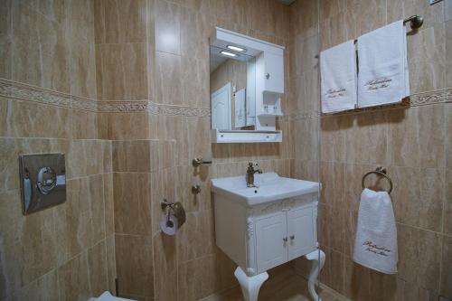 a bathroom with a white sink and a mirror at Pulpudeva Family Hotel in Plovdiv