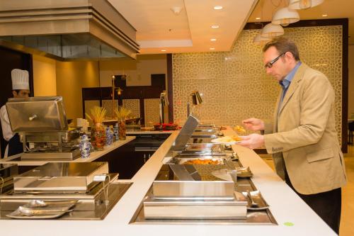 a man standing in a kitchen preparing food at Holiday Inn Yanbu by IHG in Yanbu
