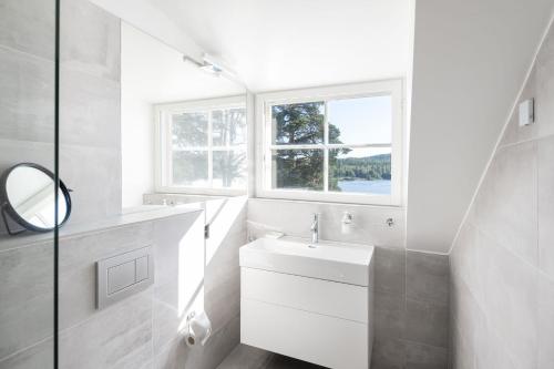 W białej łazience znajduje się umywalka i lustro. w obiekcie Ilola Inn w mieście Sysmä