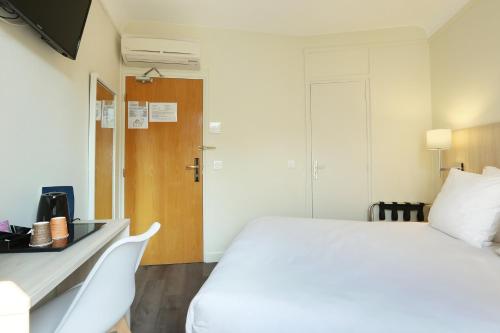 a hotel room with a white bed and a desk at Murat in Paris