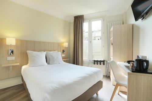 a hotel room with a large white bed and a desk at Murat in Paris