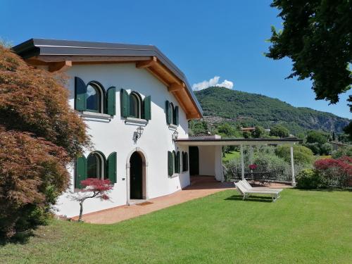 a white house with green shutters and a bench at Villa Daniela in Riva di Solto