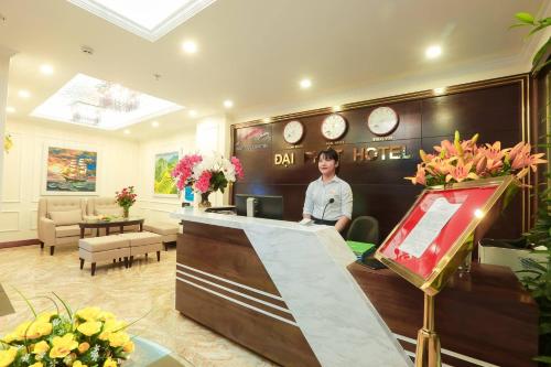 a man standing behind a counter in a hotel lobby at Dai Phat Hotel in Hanoi