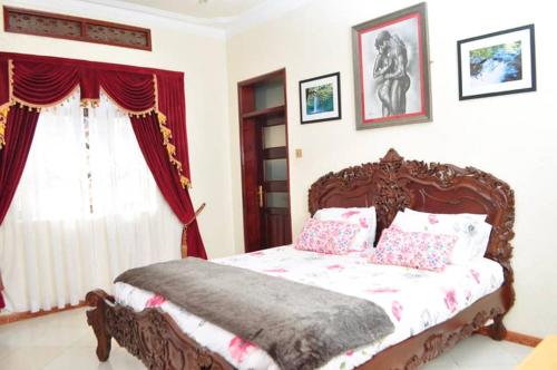 - une chambre avec un lit en bois, des oreillers et une fenêtre dans l'établissement Plot 4 Kavuma Close, à Kampala