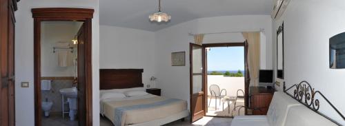 Hotel Resort Nuraghe Arvu في كالا غونوني: غرفة نوم بسرير وحمام مع شرفة