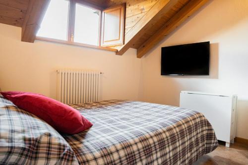 a bedroom with a bed with red pillows and a flat screen tv at Mansarda Villa Adele in Santo Stefano dʼAveto