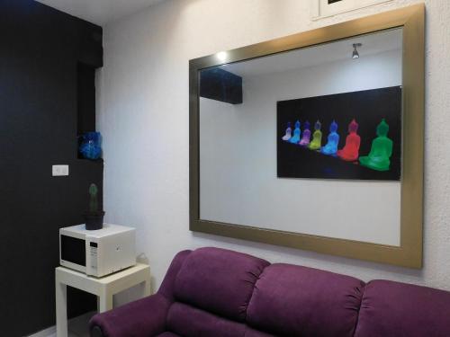 a living room with a purple couch and a mirror at Zyan Rooms in Villahermosa