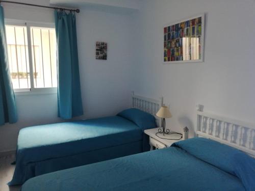 sypialnia z dwoma łóżkami i stołem z lampą w obiekcie Apartamento con vistas al mar en Carboneras w mieście Carboneras