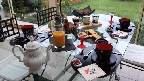 a table with a teapot and cups and food on it at CHAMBRE PRIVEE AVEC SALON, garage voiture, vélos, motos in Tourville-sur-Arques