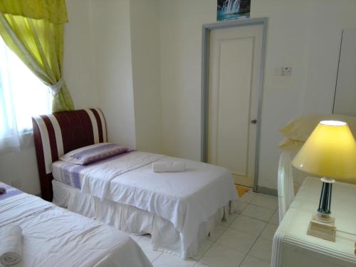a bedroom with two beds and a lamp on a table at Costa Mahkota (Family Homestay) @ Mahkota Melaka in Melaka