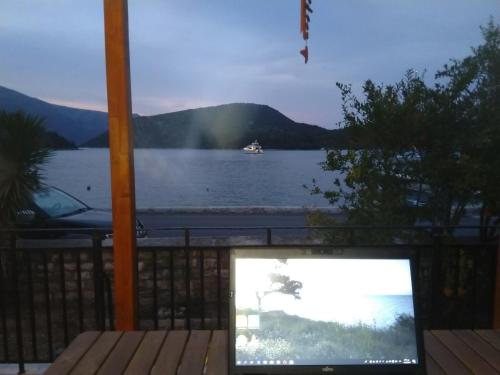 a television sitting on a deck with a view of a lake at BARRACKS 1856 in Vathi, Ithaka
