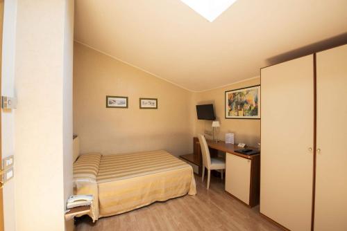 オージモにあるHotel Cristoforo Colomboのベッドとデスクが備わるホテルルームです。