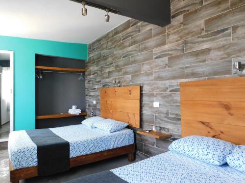a bedroom with two beds and a brick wall at Zyan Rooms in Villahermosa