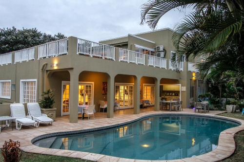 a house with a swimming pool in front of it at Caza Beach Guesthouse in Durban