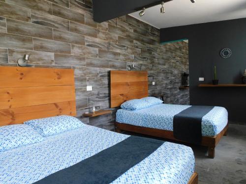 a bedroom with two beds and a stone wall at Zyan Rooms in Villahermosa