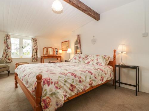 a bedroom with a bed with a floral bedspread at Church Farmhouse in Winsham