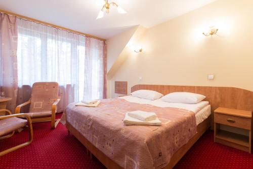 a bedroom with a bed and a chair and a window at Paradiso Park in Pobierowo