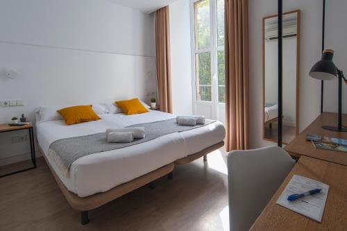 a bedroom with a bed with yellow and orange pillows at Pensión Sarriegi in Donostia-San Sebastián