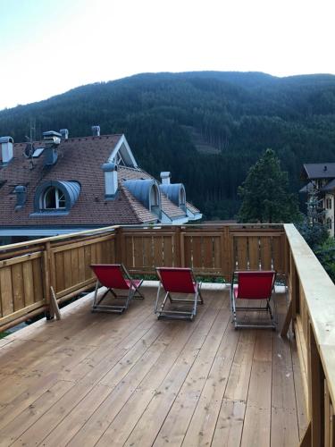 3 sillas en una terraza con montañas al fondo en Hotel Residence Lorenz, en Colle Isarco