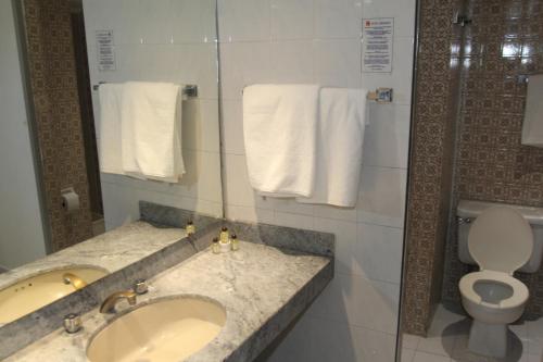 a bathroom with a sink and a toilet and towels at Hotel Universo in Guadalajara