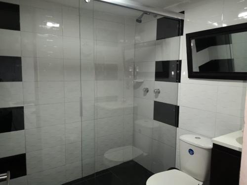 a bathroom with a toilet and a glass shower at Hotel Santiago Plaza in Bogotá