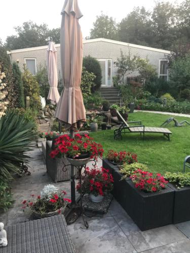 a patio with an umbrella and flowers in a yard at Villa 't Haasduin in Wijk aan Zee