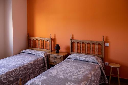 Duas camas num quarto com paredes cor de laranja em El Gavilán em Villaviciosa