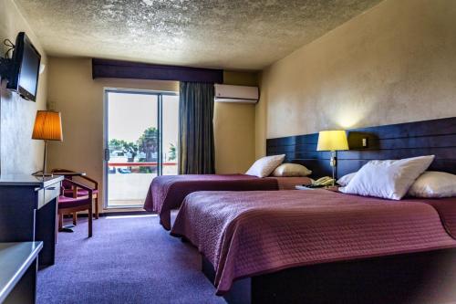 a hotel room with two beds and a window at Hotel Posada Don Fernando in Ensenada