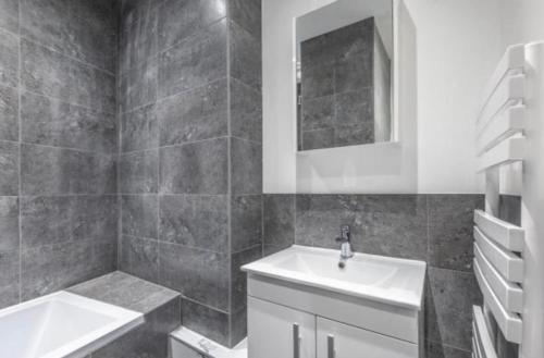 a black and white bathroom with a sink and a mirror at Premium Apartments Thatcham Broadway in Thatcham
