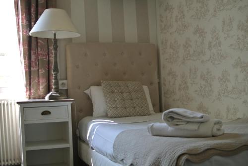 a small bedroom with a bed with a lamp and a table at Logis Hôtel Louise de Savoie in Blois